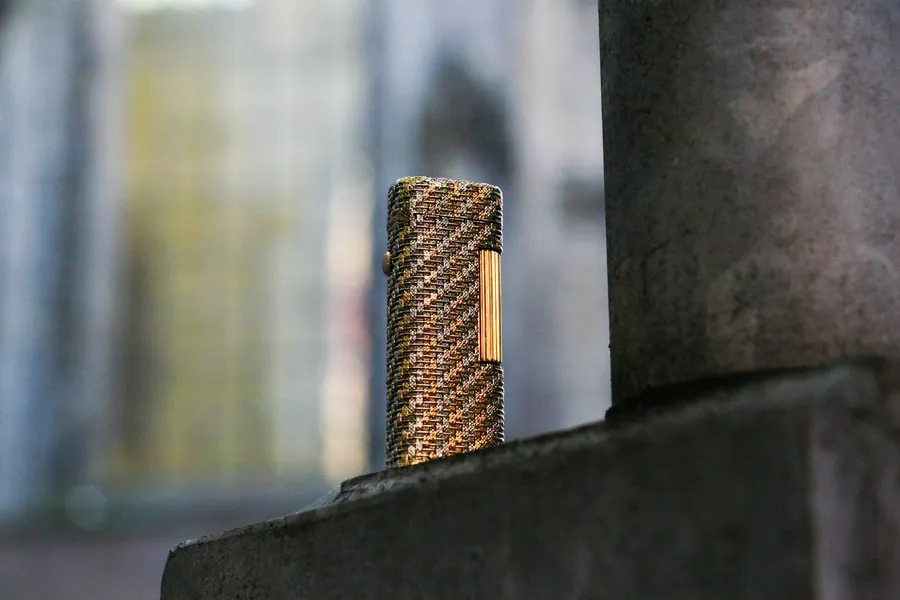 Solid gold Dunhill lighter with a woven pattern on a stone ledge